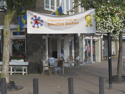 908174 Afbeelding van het spandoek met de tekst 'Oog in Al is trots op gouden Dafne', opgehangen bij Carla's Conditorie ...
